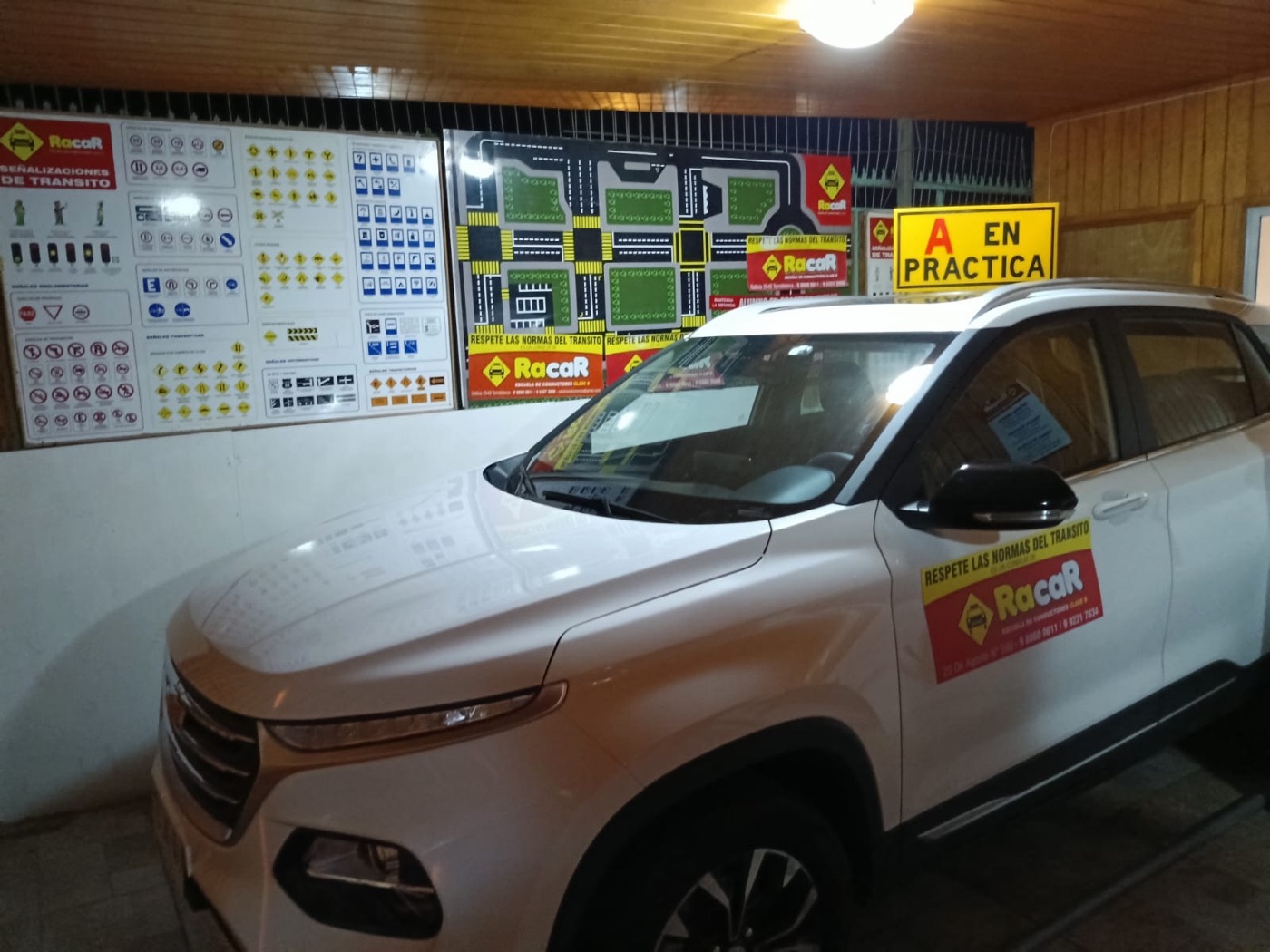 Auto blanco de la escuela con el cartel A en práctica frente a los paneles de señalizaciones