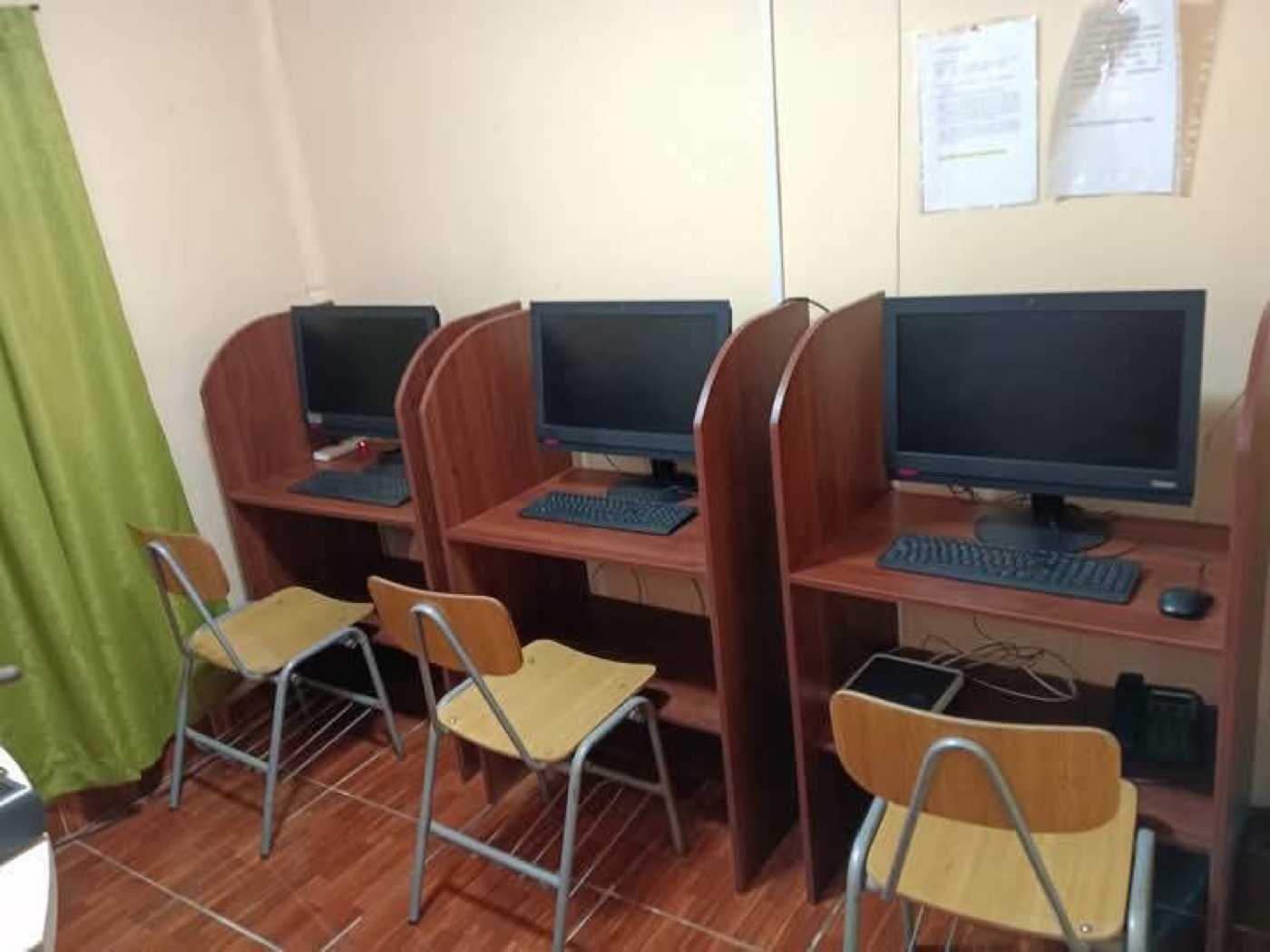 Tres computadores en cubículos de madera con sillas