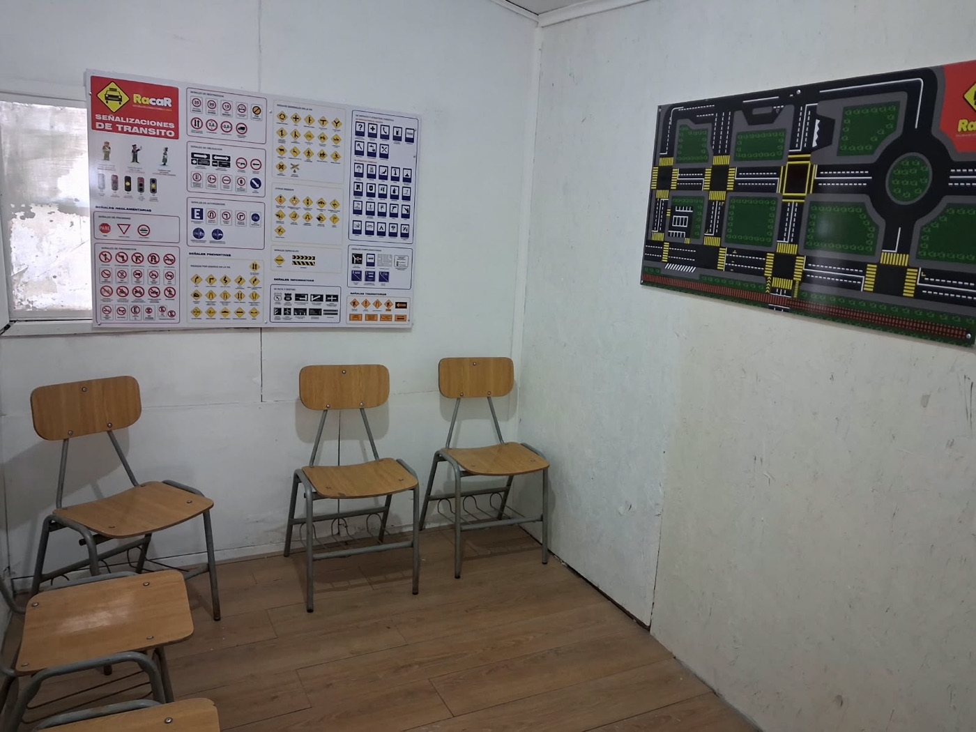Sala de clases con sillas, un panel de señalizaciones de tránsito y un mapa de calles para practicar